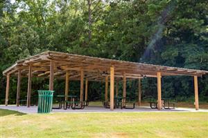 Ann Pearson Park Pavilion - Wooden pavilion with metal covering with picnic tables and trash cans.