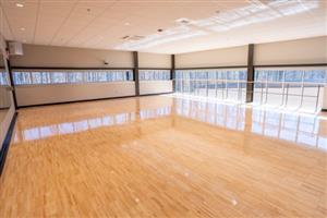 Fitness studio with wooden floors and windows.