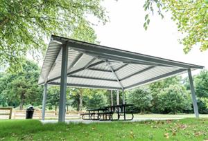 Pavilion with metal covering, picnic tables, and trash can.